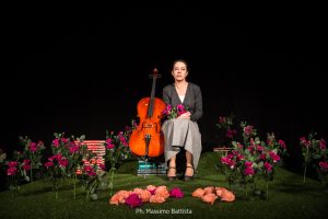 woman sitting at graveyard with books and a cello